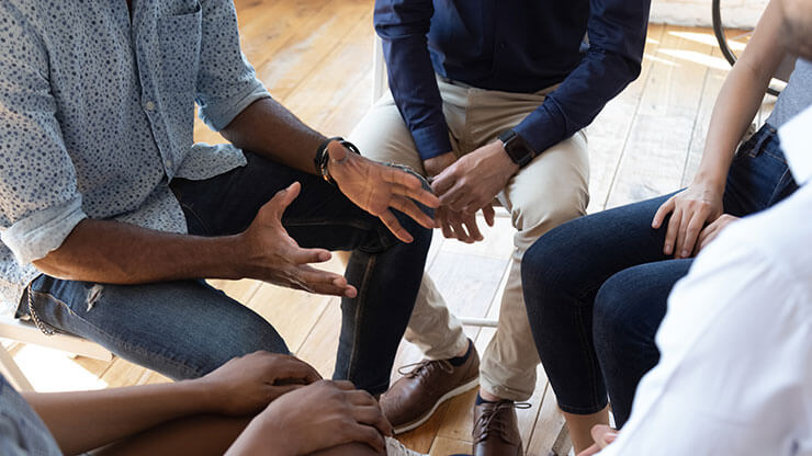 Closeup of lower bodies of a group of people in a counseling circle